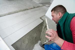 trabajador instalando las baldosas cerámicas con efecto madera en el suelo foto