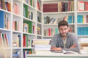 portrait of student while reading book  in school library photo