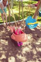 mother and daughter swinging in the park photo