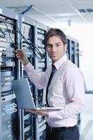 businessman with laptop in network server room photo