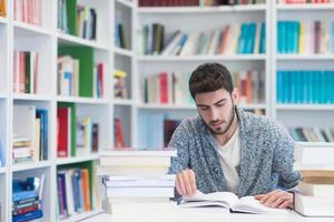 portrait of student while reading book  in school library photo