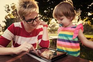 mom and her little daughter using tablet computer photo