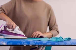 Red haired woman ironing clothes at home photo