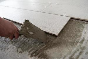 worker installing the ceramic wood effect tiles on the floor photo