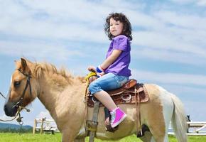 niño montar pony foto