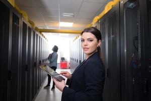 Female engineer working on a tablet computer in server room photo