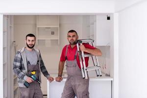 jóvenes trabajadores instalando una nueva cocina foto