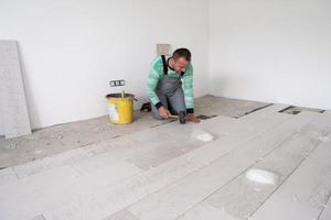 worker installing the ceramic wood effect tiles on the floor photo