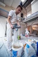 construction worker mixing plaster in bucket photo