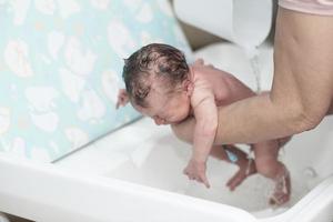 Newborn baby girl taking a first bath photo