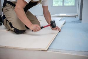 trabajador profesional instalando un nuevo piso de madera laminada foto