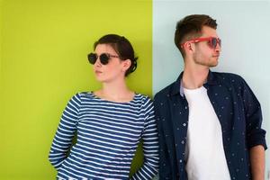 Beautiful young loving couple adjusting their sunglasses while standing against green-grey background photo