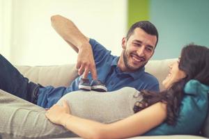 young pregnant couple relaxing on sofa photo