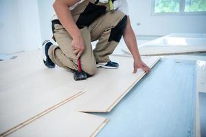 Professional Worker Installing New Laminated Wooden Floor photo