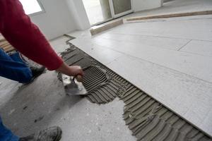 worker installing the ceramic wood effect tiles on the floor photo