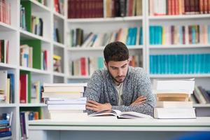 portrait of student while reading book  in school library photo