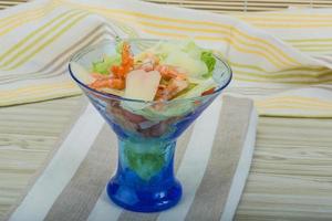 Caesar salad with shrimps in a bowl on wooden background photo