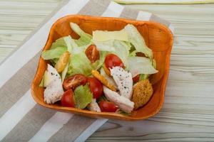 Caesar salad with chicken in a bowl on wooden background photo