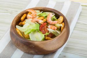 Caesar salad with shrimps in a bowl on wooden background photo