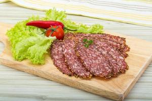 Sliced salami on wooden board and wooden background photo