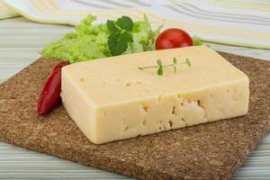 Yellow cheese on wooden board and wooden background photo