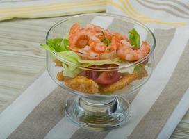 Caesar salad with shrimps in a bowl on wooden background photo