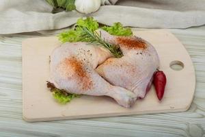 Chicken thigh on wooden board and wooden background photo