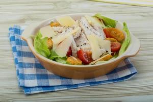 Caesar salad with chicken in a bowl on wooden background photo