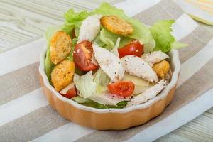 Caesar salad with chicken in a bowl on wooden background photo