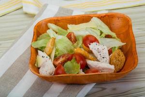 Caesar salad with chicken in a bowl on wooden background photo