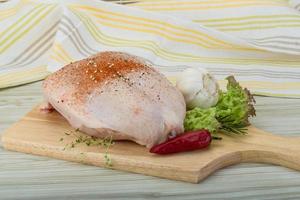 Raw chicken breast on wooden board and wooden background photo