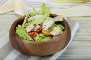 Caesar salad with chicken in a bowl on wooden background photo