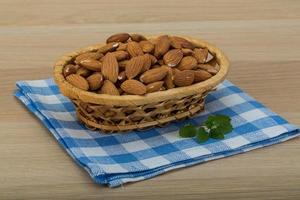 Almond in the bowl in a basket on wooden background photo