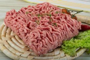 Minced meat on wooden board and wooden background photo