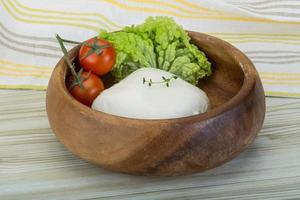 Mozzarella in a bowl on wooden background photo