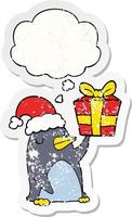 cartoon penguin with christmas present and thought bubble as a distressed worn sticker vector