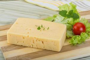 Yellow cheese on wooden board and wooden background photo