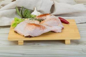 Chicken thigh on wooden board and wooden background photo