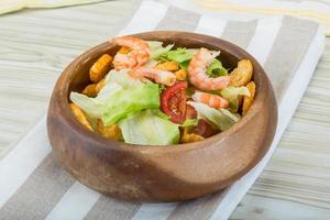 Caesar salad with shrimps in a bowl on wooden background photo