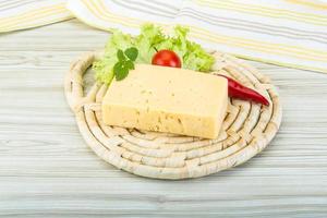 Yellow cheese on wooden board and wooden background photo