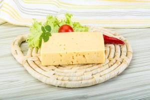 Yellow cheese on wooden board and wooden background photo