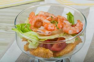 Caesar salad with shrimps in a bowl on wooden background photo