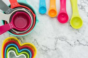 Set of measuring cups, measuring spoons and plastic cookie cutters use in cooking lay on marble tabletop photo
