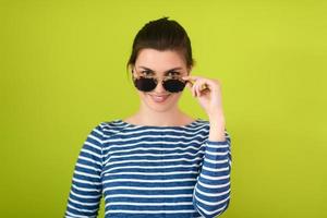 mujer con gafas de sol posando frente a un fondo verde foto