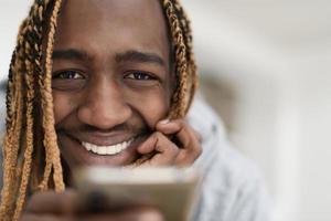 chico afro usa un teléfono celular y navega por las redes sociales durante una pandemia foto