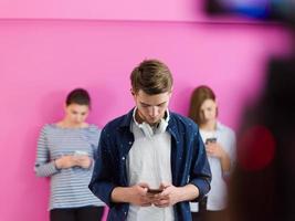 grupo de adolescentes diversos usan dispositivos móviles mientras posan para una foto de estudio