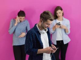 group of diverse teenagers use mobile devices while posing for studio photo