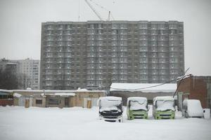 Cityscape in winter. View of construction site of house. Parking for buses. photo