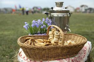 Russian treats. Sweetness from flour. Basket of dry stems. Steel kettle. Folk tradition. photo