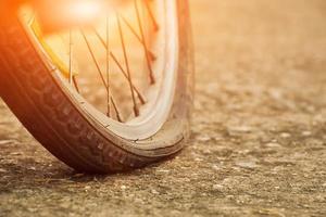 Close up view of bike which has flat tire and parked on the pavement, blurred background. Soft and selective focus on tire. photo